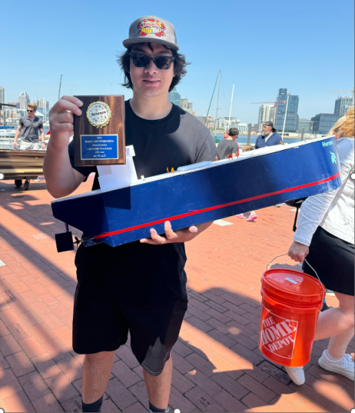 Senior Phil Lewis poses with his teams first place award on Sunday in Inner Harbor.